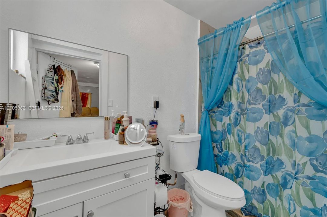 White vanity featuring a rectangular integrated sink, chrome faucet, and storage cabinetry with polished hardware, complemented by a large wall-mounted vanity mirror