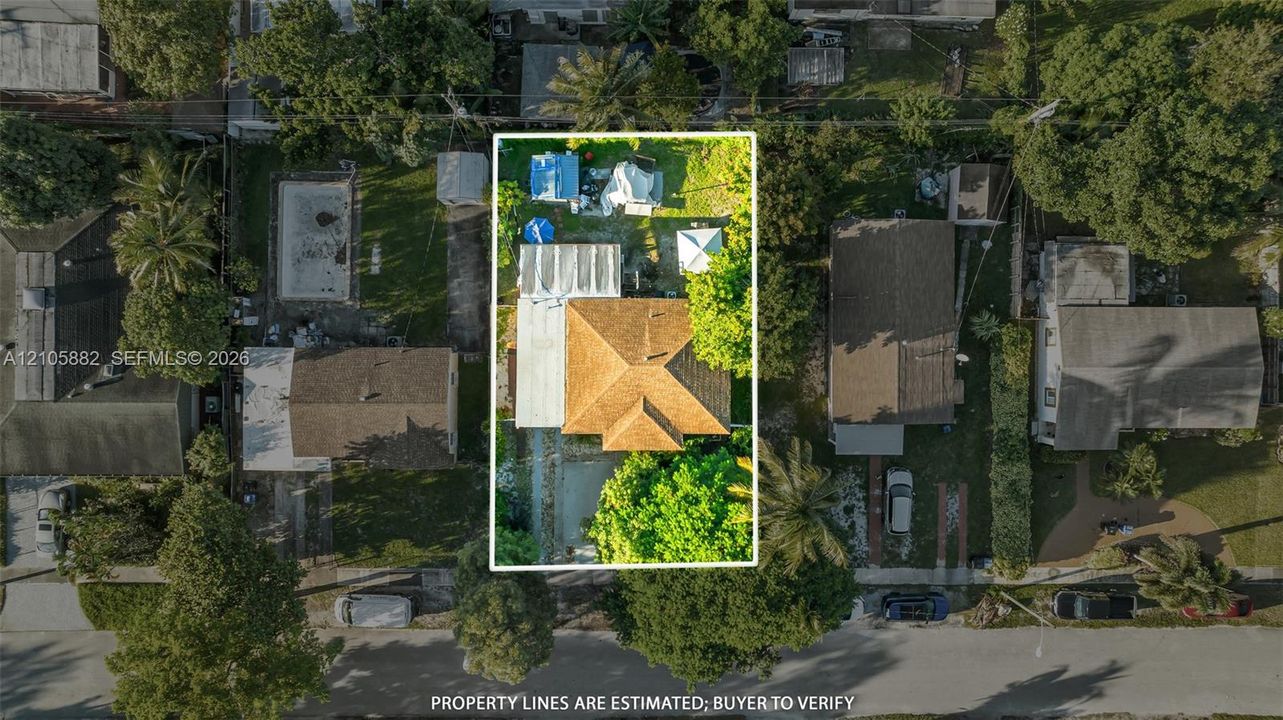 Aerial perspective of a residential lot featuring a hip roof structure, an attached covered patio, a concrete driveway, and established perimeter landscaping