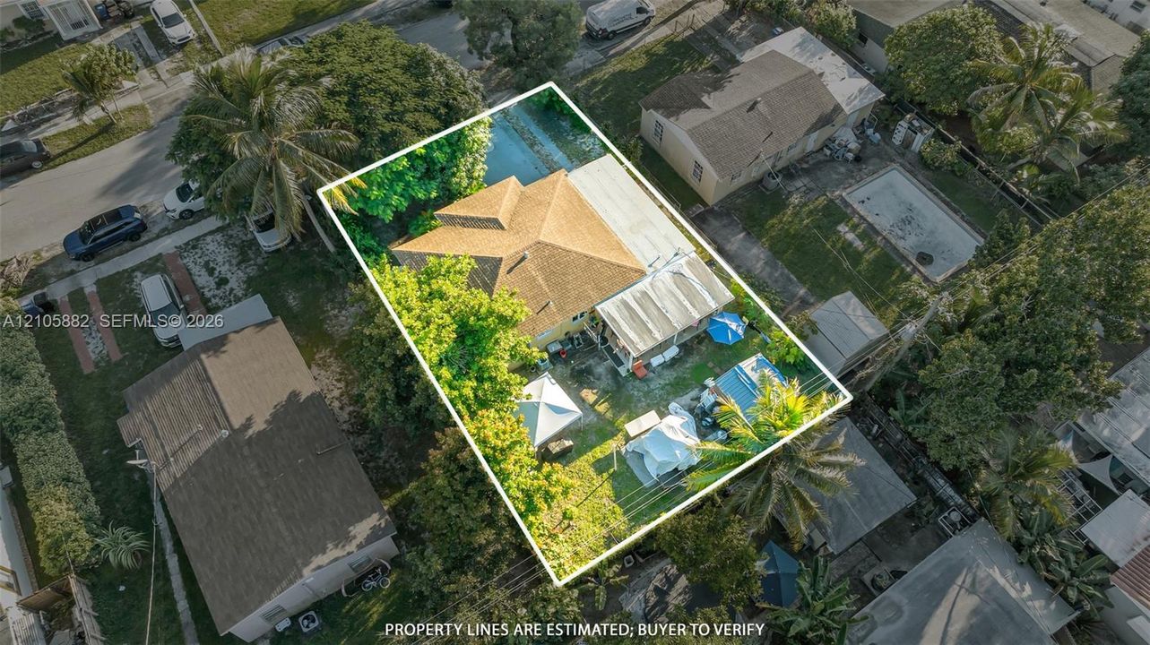 Aerial perspective of a detached residential property featuring a hipped roof, covered rear patio, and mature trees situated on a fenced lot