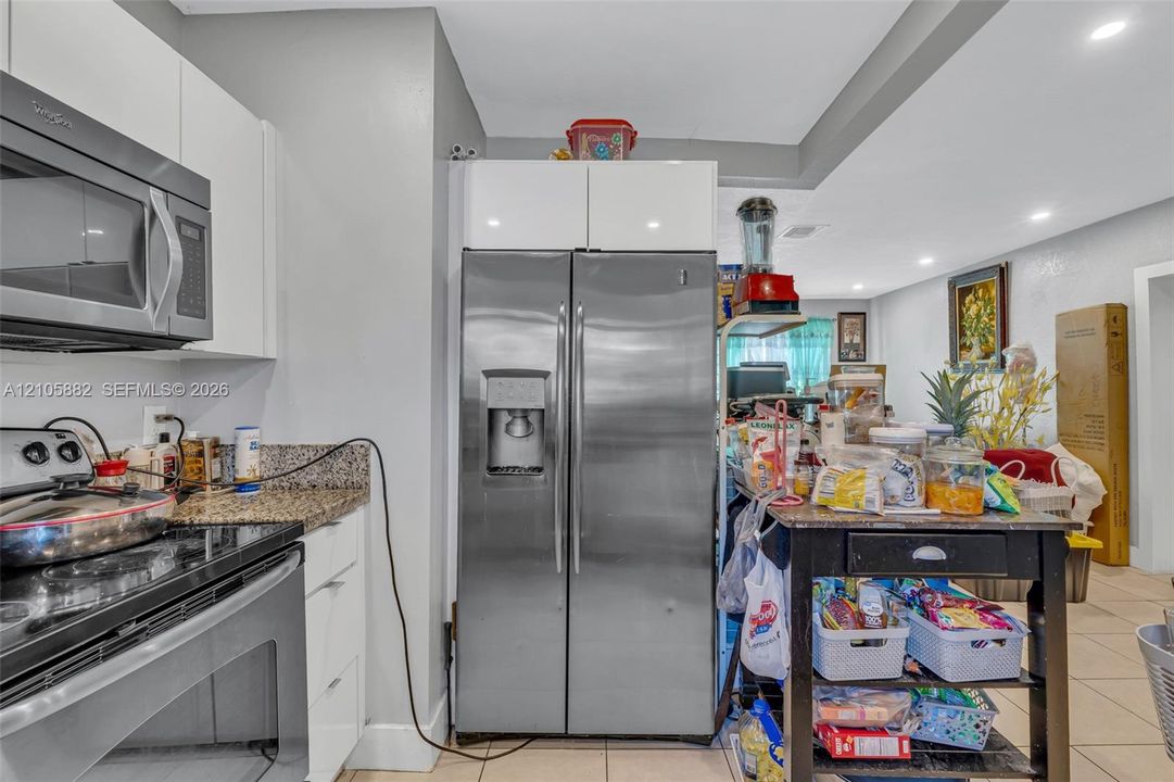 Kitchen featuring high-gloss white cabinetry, stainless steel appliances, stone countertops, and recessed ceiling lighting