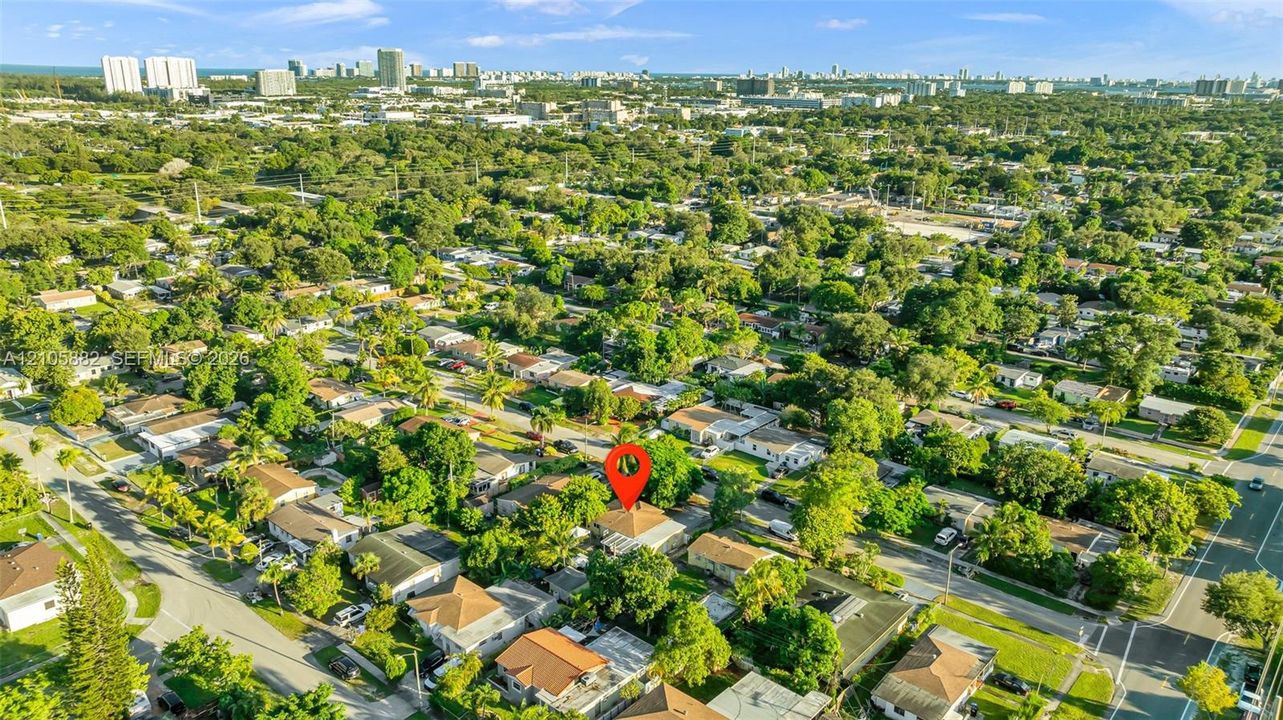 Aerial perspective featuring a residential lot with mature trees and a location marker, positioned within an established suburban setting