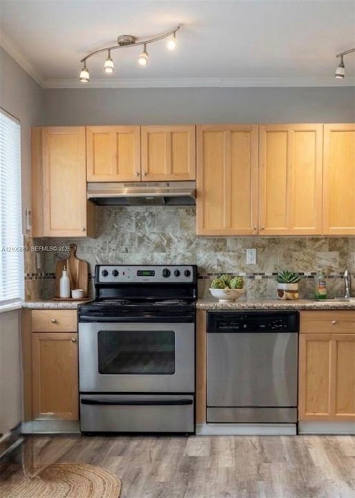 Kitchen featuring light-finish cabinetry, stone-texture backsplash, stainless steel appliances, speckled countertops, and track lighting