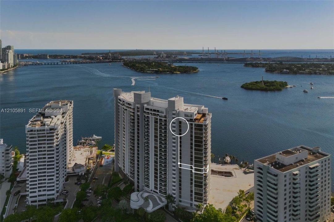 High-rise residential building featuring expansive floor-to-ceiling windows, private balconies, and waterfront positioning