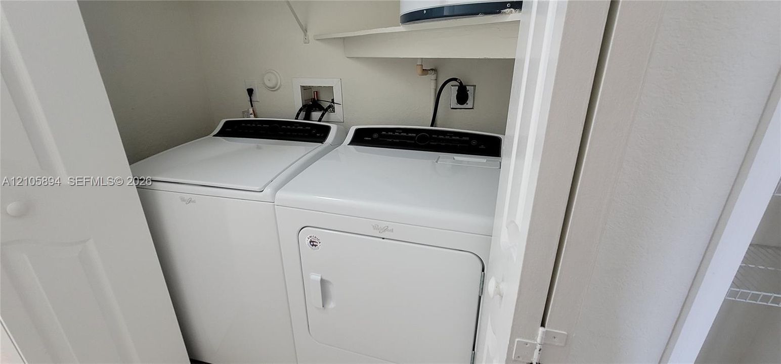 Dedicated laundry space featuring built-in shelving and installed utility connections