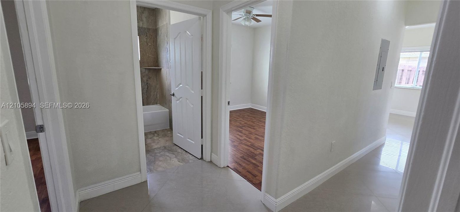Interior hallway with neutral tile flooring, wood-finish flooring in secondary rooms, and multi-panel interior doors