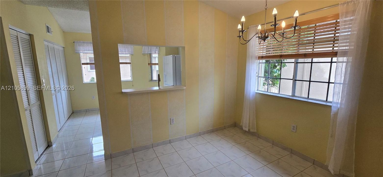 Ceramic tile flooring, pass-through window, six-light chandelier, and multi-pane windows with louvered blinds