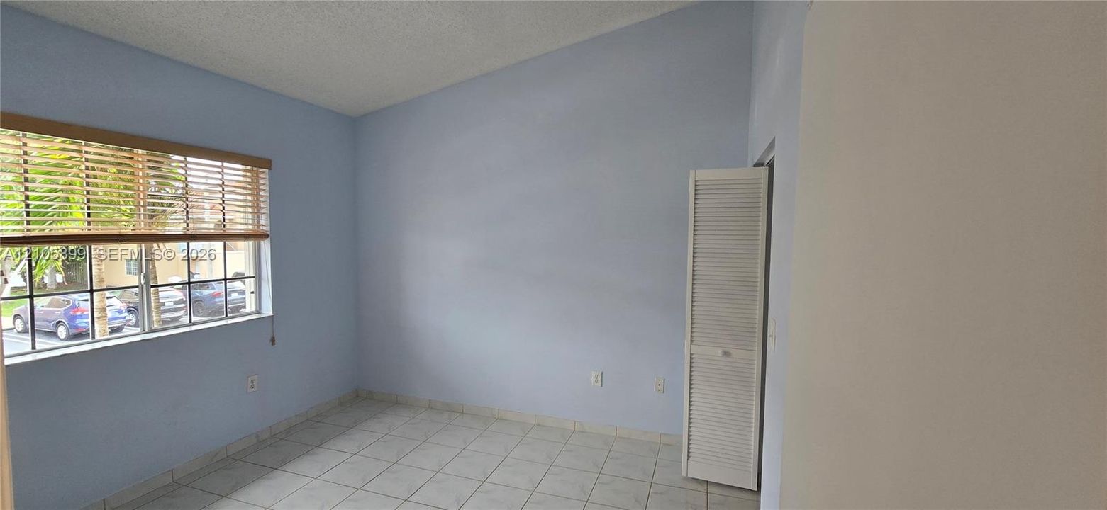 Vaulted ceiling, ceramic tile flooring, horizontal window blinds, and louvered closet doors