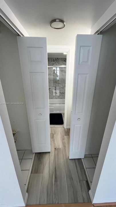 White bi-fold doors, wood-finish flooring, and a flush-mount ceiling fixture