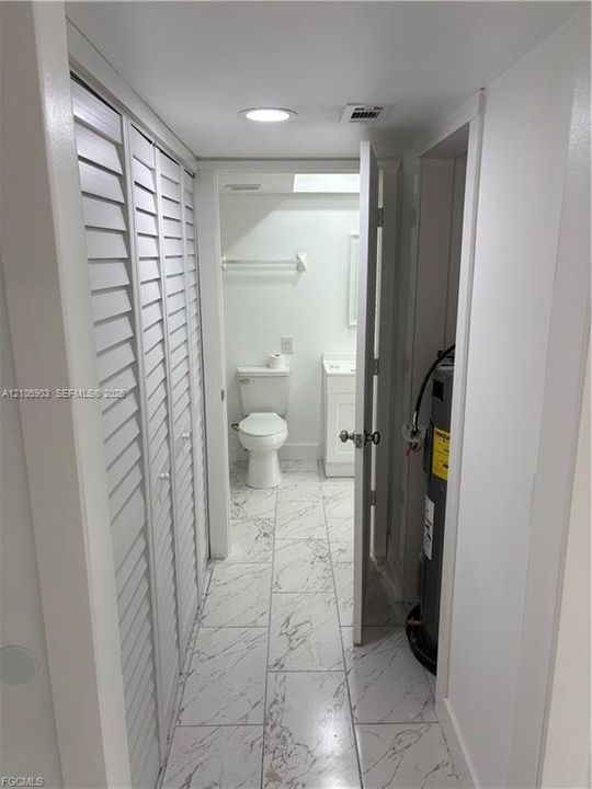 Large-format tile flooring, louvered bi-fold closet doors, recessed lighting, and built-in vanity cabinetry