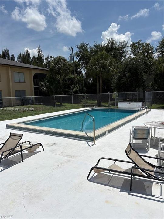 In-ground swimming pool featuring tile coping, a metal handrail, and a concrete deck