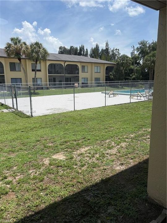 Common area featuring a swimming pool, concrete pool deck, and chain-link perimeter fencing, situated within a landscaped lawn area