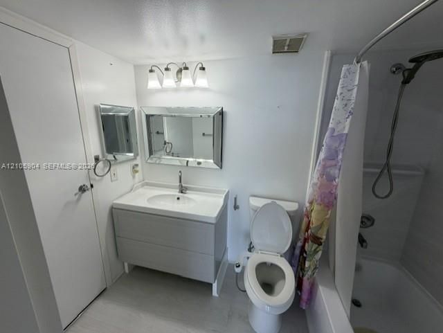 Bathroom featuring a gray vanity with an integrated sink, a beveled-edge mirror, a three-light vanity fixture, and a shower-tub combination with a handheld showerhead