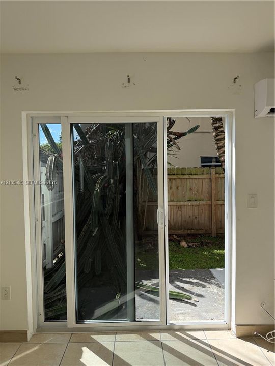 White-frame sliding glass door with large-format floor tile and a wall-mounted climate control unit