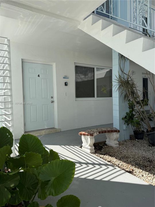 Exterior entryway featuring a solid-panel door, horizontal sliding window, concrete landing, and decorative wrought iron stair railing