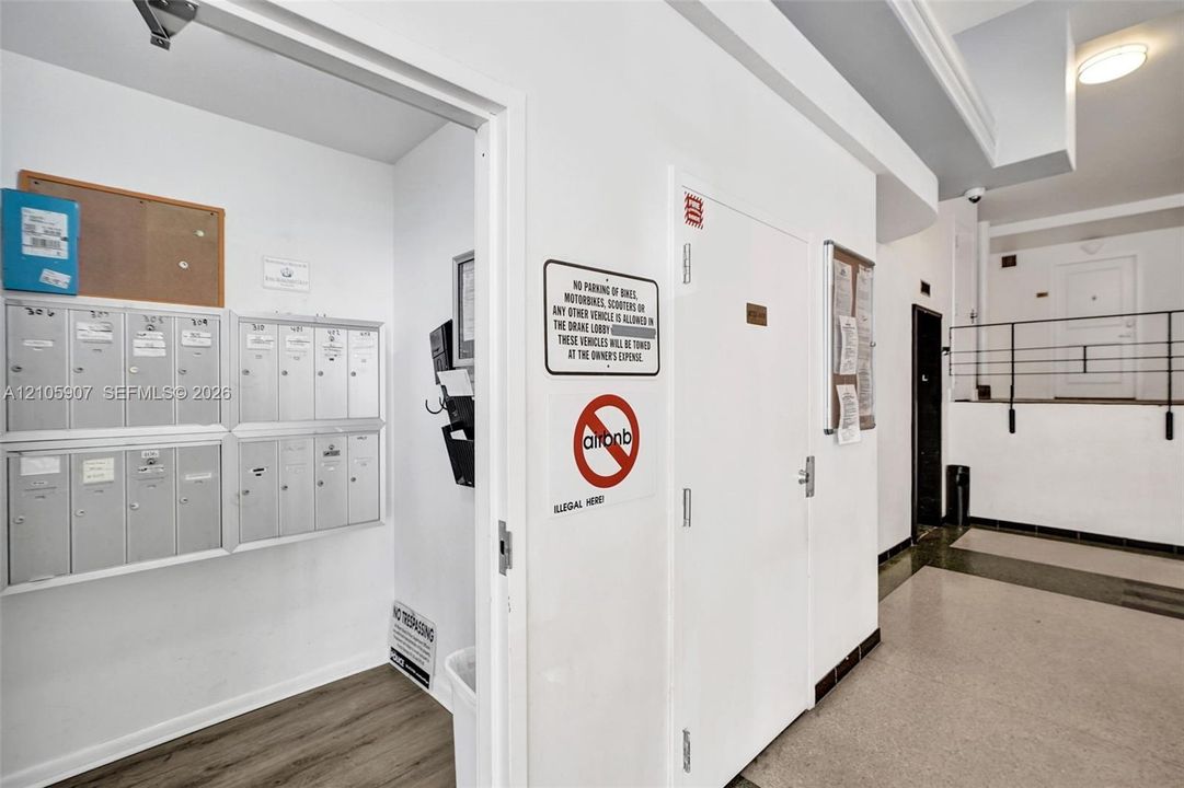 Building lobby featuring a wall-mounted metal mailbox bank, wood-finish flooring, and recessed ceiling lighting