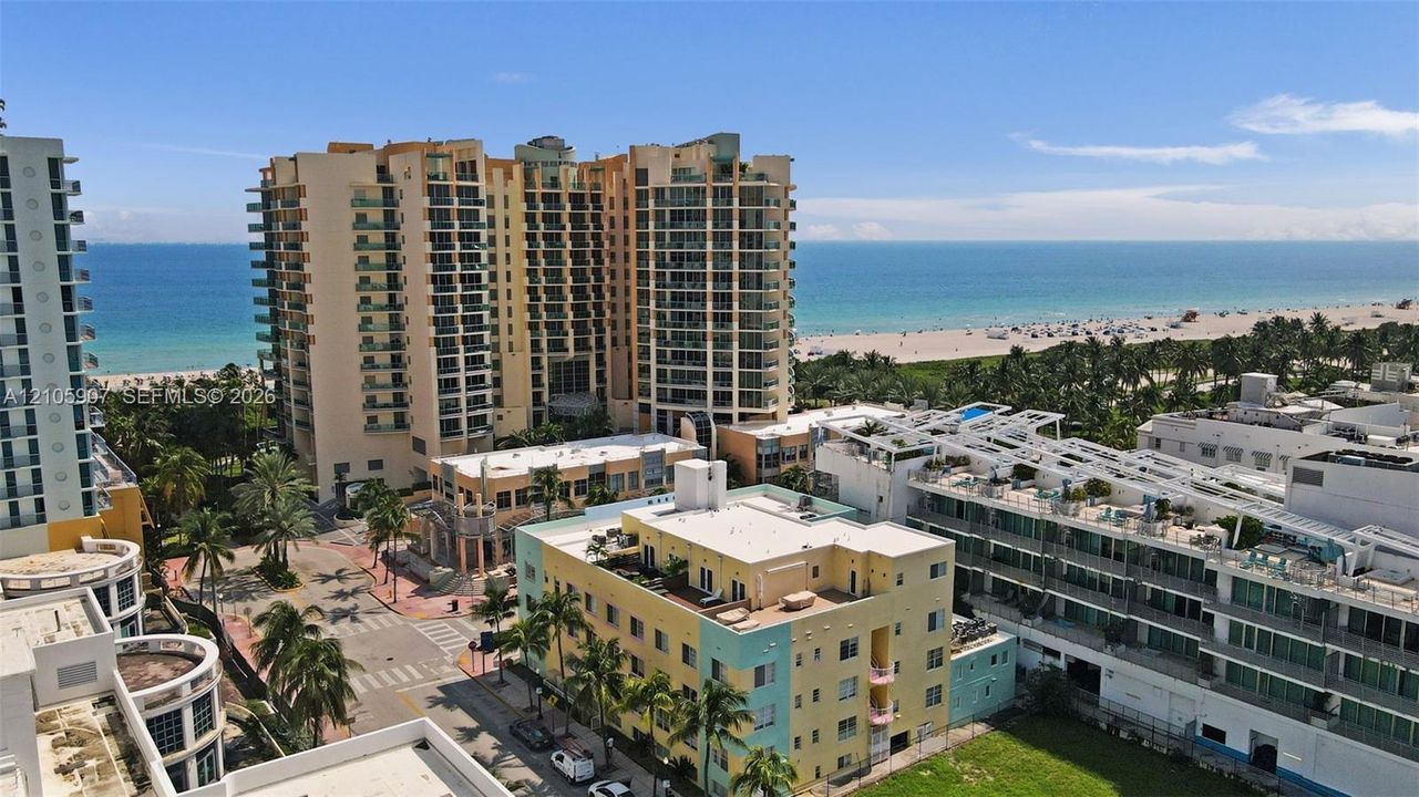 High-rise coastal residential structures featuring expansive glass balcony railings, prominent oceanfront proximity, and established tropical landscaping
