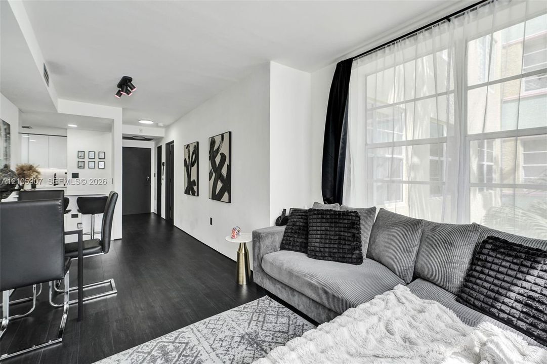 Living area featuring wood-finish flooring, large multi-pane windows, recessed ceiling lighting, and a neutral color palette