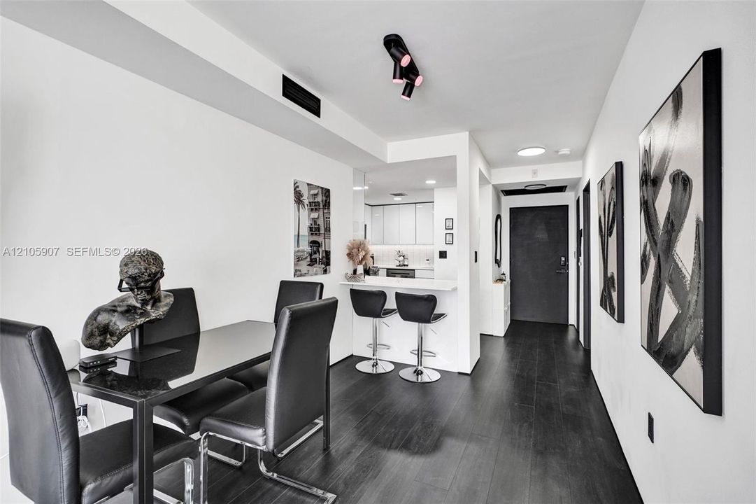 Open-concept interior featuring dark wood-finish flooring, matte black track lighting, and a breakfast bar with stone-finish countertops