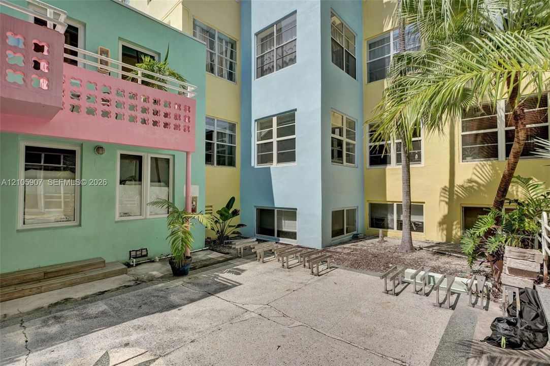 Art Deco exterior featuring multi-toned masonry, decorative breeze block balcony railings, multi-pane casement windows, and a paved courtyard