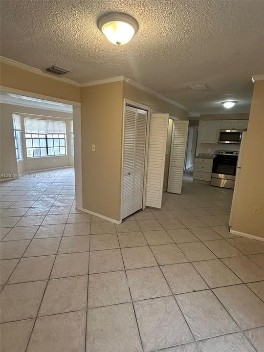 Ceramic tile flooring, white cabinetry, stainless steel kitchen appliances, and closet storage with louvered doors