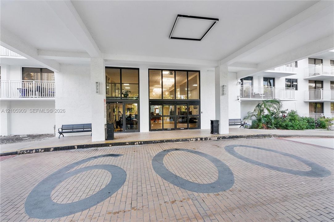 Covered porte-cochère entry featuring brick paving and glass-paneled double doors