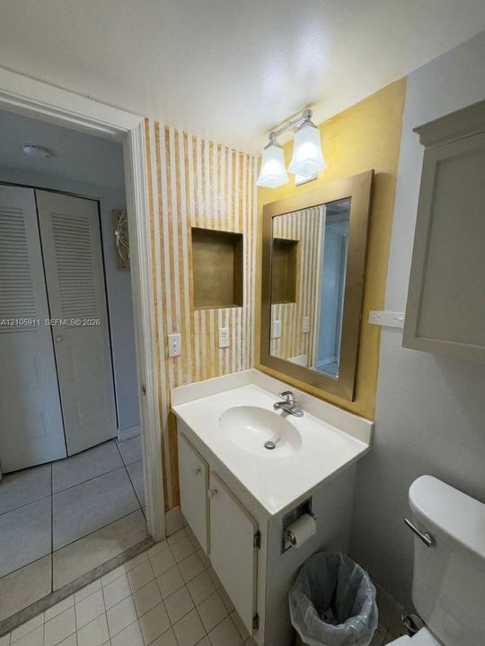 Bathroom vanity featuring an integrated oval sink, countertop with backsplash, framed mirror, built-in recessed wall shelving, and dual-light fixture