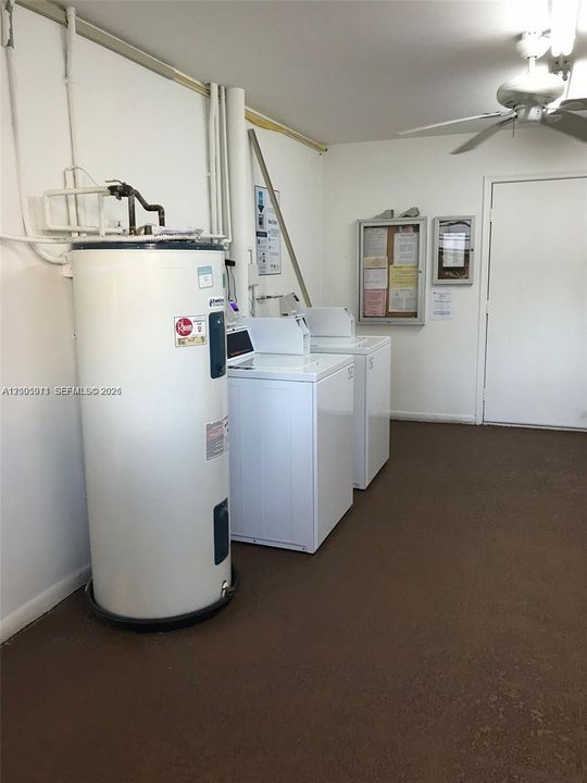 Utility space featuring a water heater, side-by-side laundry appliances, a ceiling-mounted fan, and a solid-core door