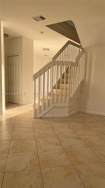 Interior featuring ceramic tile flooring, a staircase with white vertical balusters and handrails, and a solid-core interior door