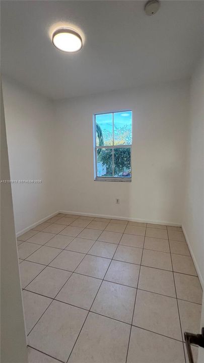 Neutral-toned tile flooring, single-hung window with exterior greenery, and flush-mount ceiling lighting
