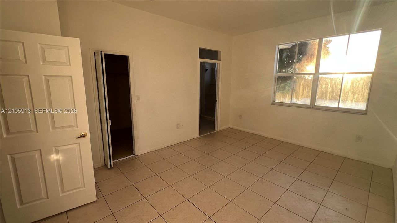 Interior room featuring neutral-toned tile flooring, a large multi-pane window, and a six-panel door