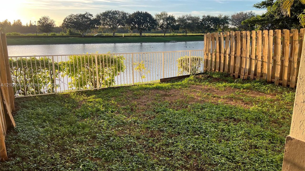 Waterfront backyard featuring a metal picket fence, wood privacy fencing, and direct water frontage