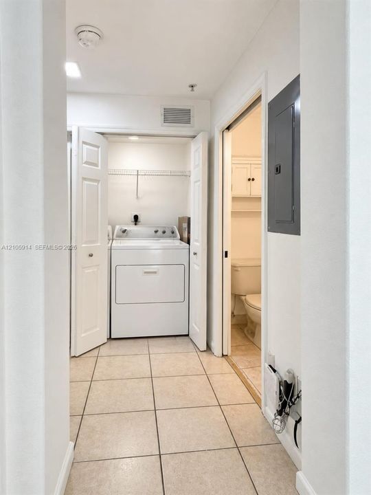 Laundry area featuring tile flooring, built-in wire shelving, and bi-fold closet doors