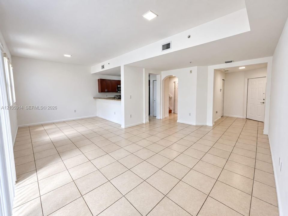 Open-concept interior featuring light-toned tile flooring, recessed lighting, a breakfast bar, and architectural arched detailing