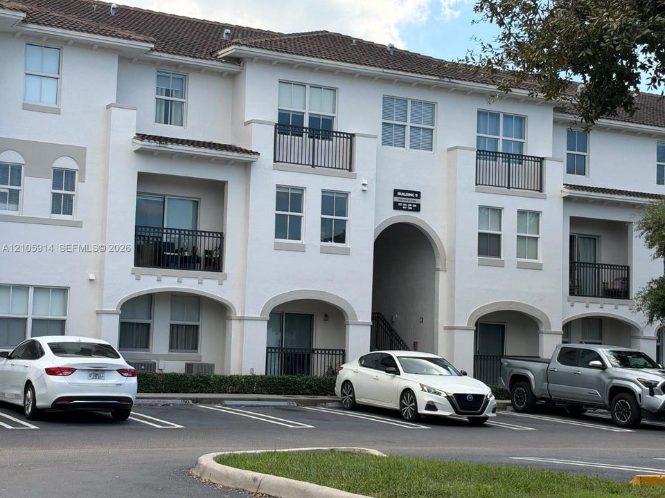 Multi-story stucco exterior featuring arched entryways, tile roof, and private railed balconies
