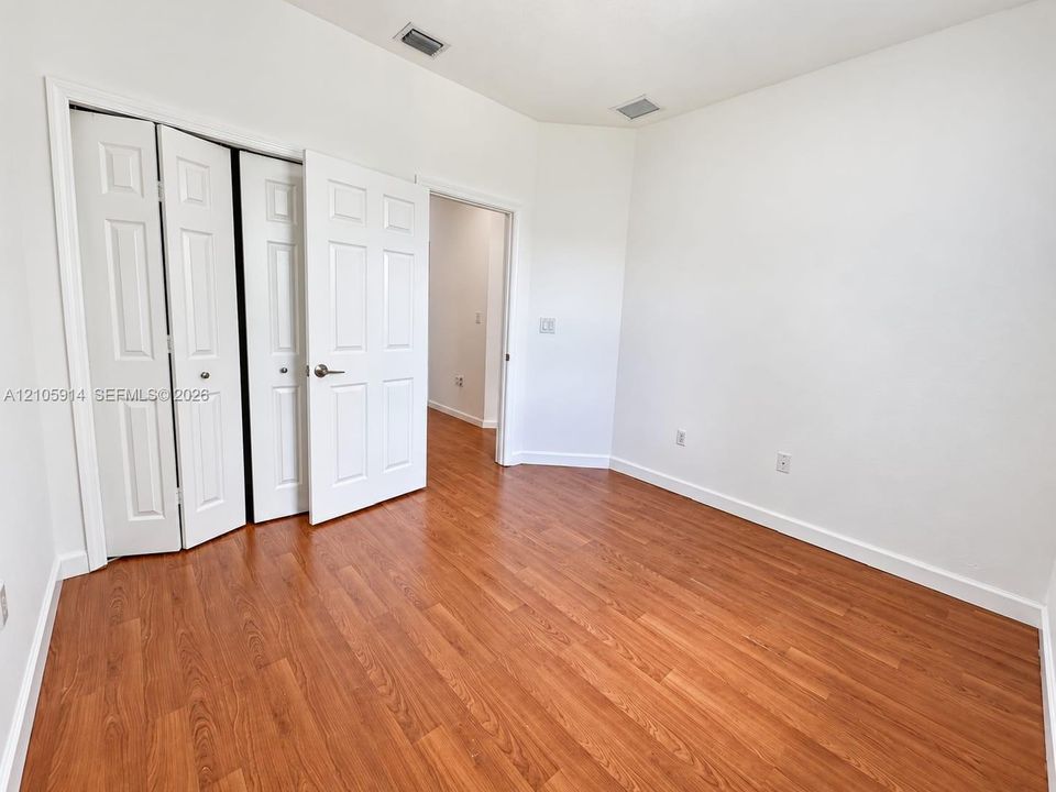 Neutral wall palette with wood-finish flooring and paneled bi-fold closet doors