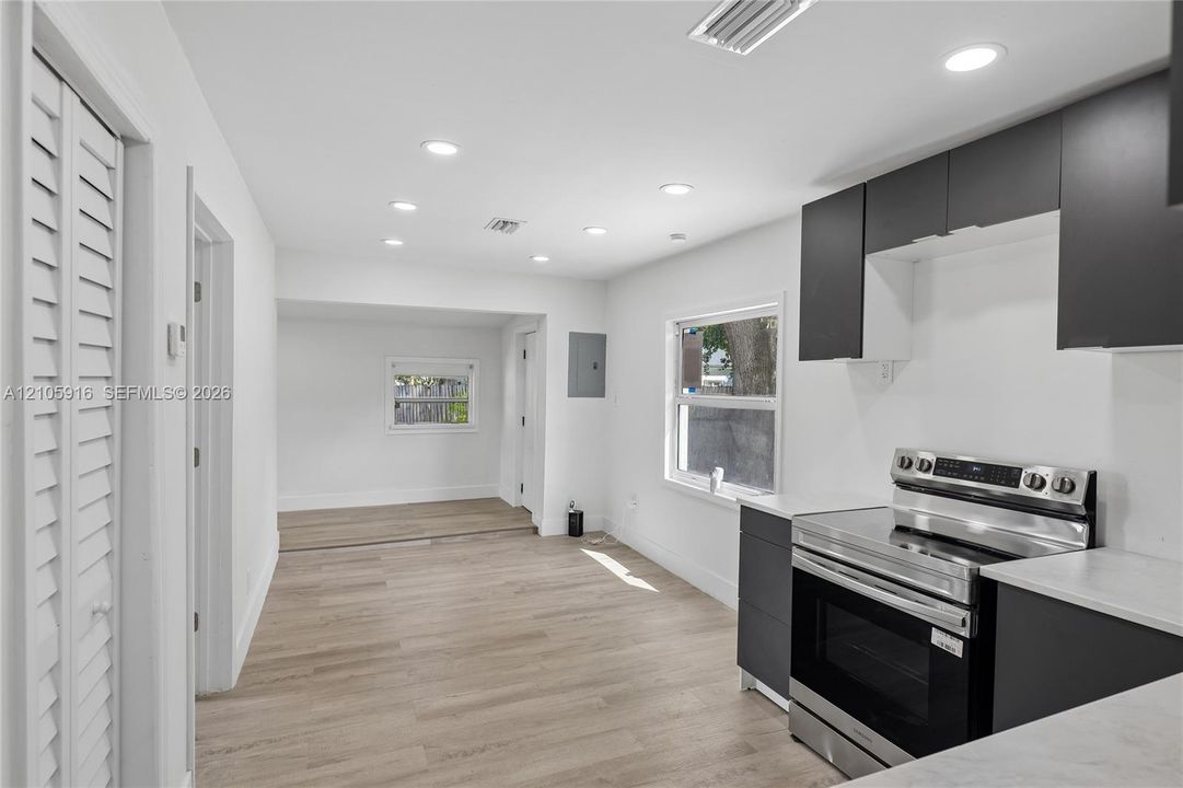 Kitchen featuring two-tone cabinetry, stainless steel range, light-toned wood-finish flooring, recessed lighting, and white countertops