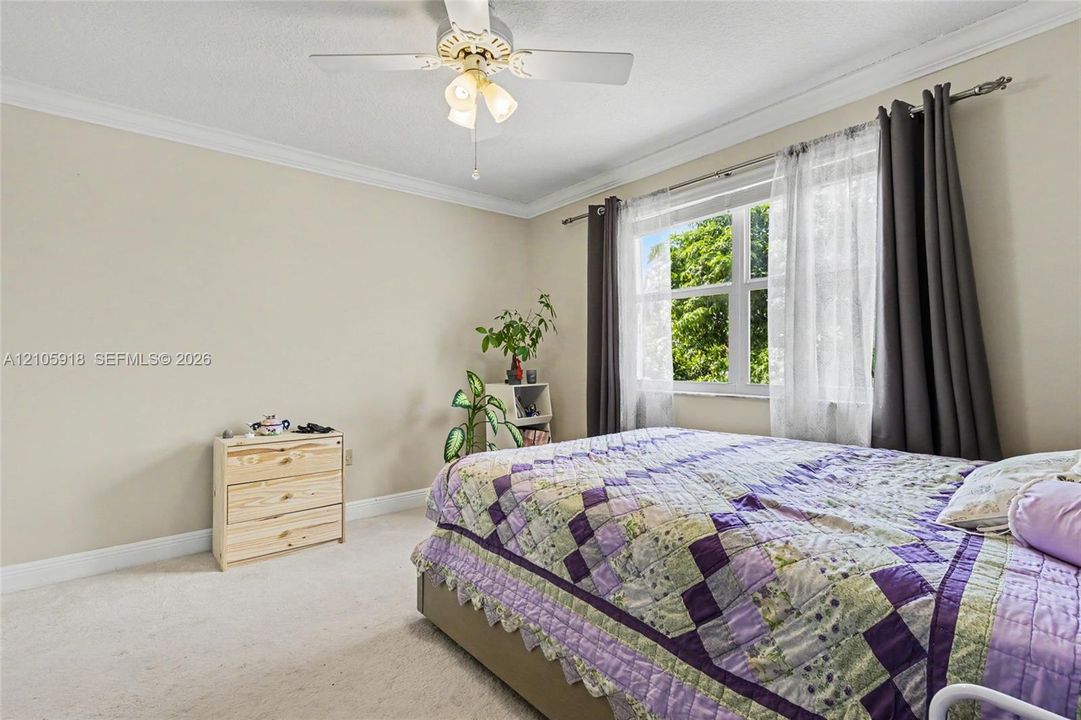 Neutral interior room featuring crown molding, carpeting, a ceiling fan with integrated lighting, and a multi-pane window