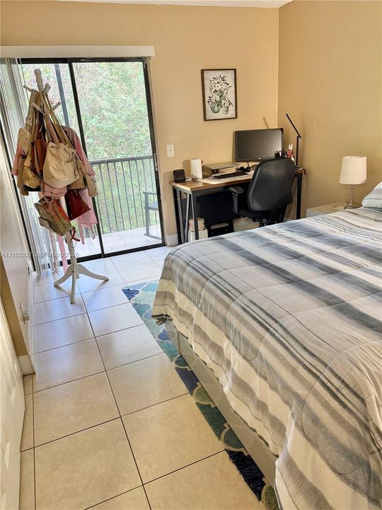 Neutral-toned room featuring large-format ceramic floor tile and a sliding glass door providing access to a private balcony with metal railing