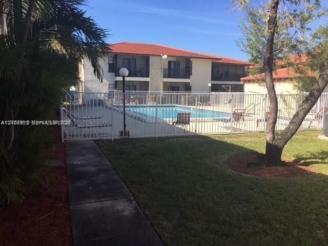 Community swimming pool featuring a concrete deck and a white metal enclosure