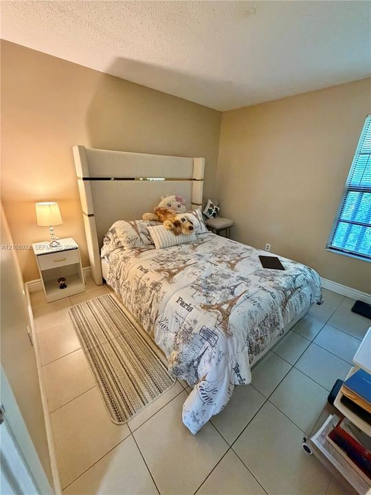 Room featuring light-toned neutral wall paint, large-format tile flooring, and a window with horizontal blinds