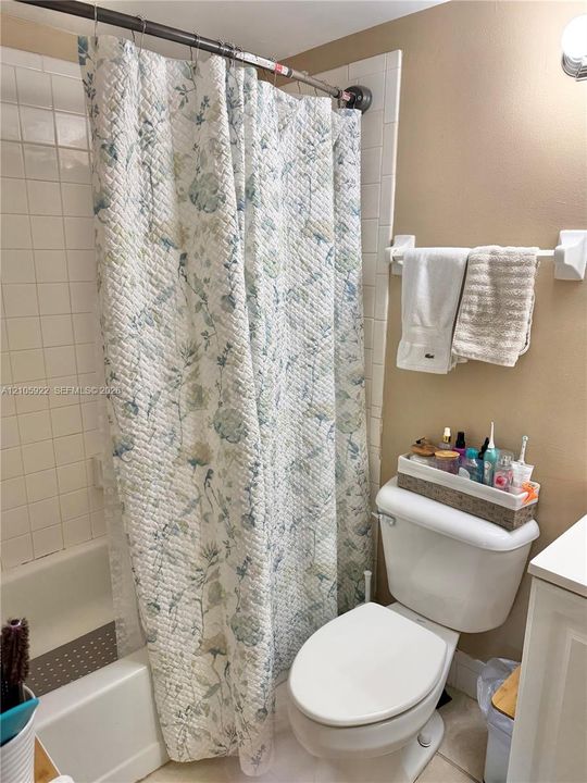 Full-size bathtub with surrounding square tile wall finish and attached wall-mounted towel bar