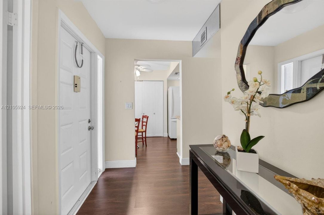 Foyer featuring wood-finish flooring, a six-panel entry door, and neutral wall paint