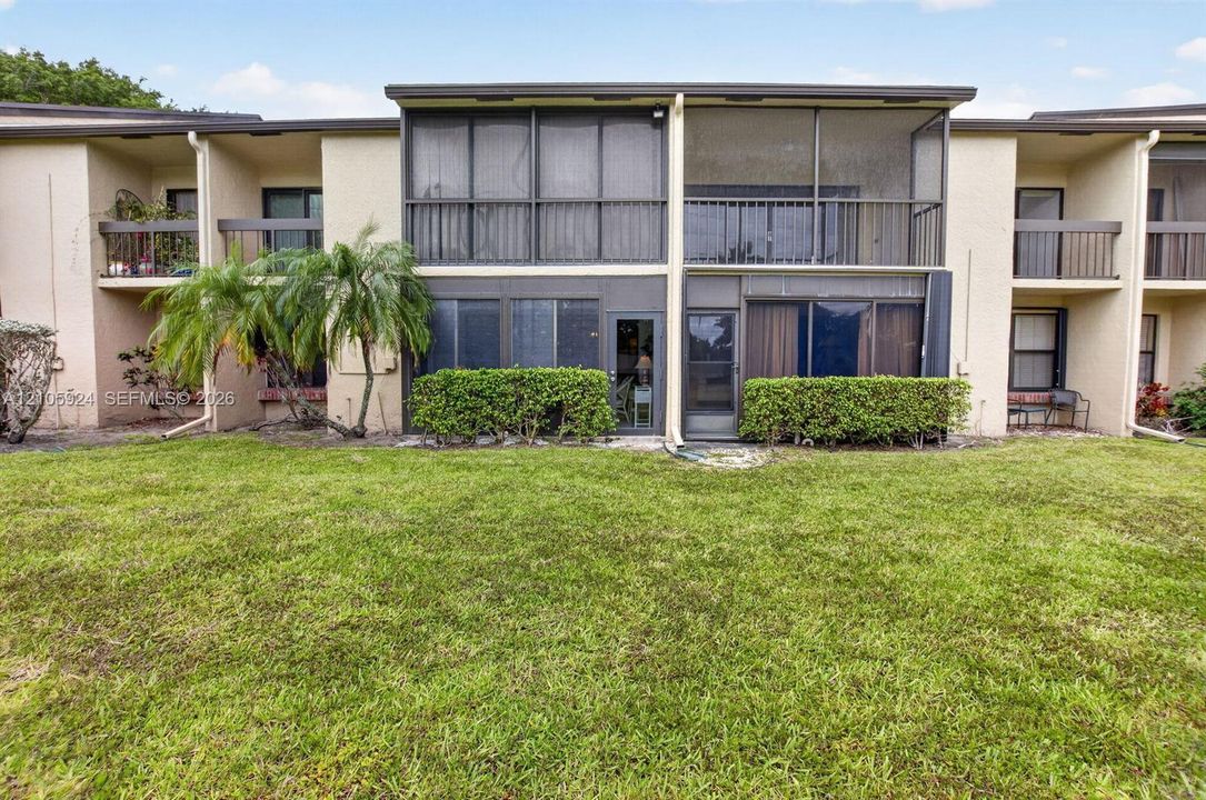 Multi-level exterior featuring screened-in lanais, stucco siding, and ground-level landscaping
