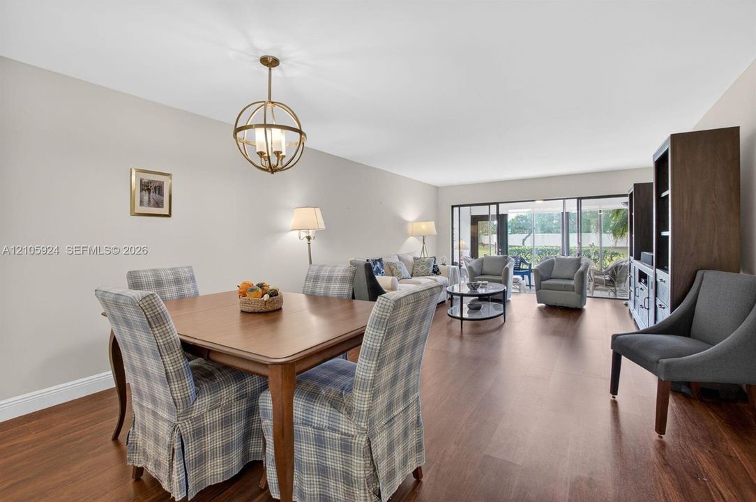 Open-concept living space featuring wood-finish flooring, a contemporary spherical metal pendant light, and sliding glass doors with dark-toned frames