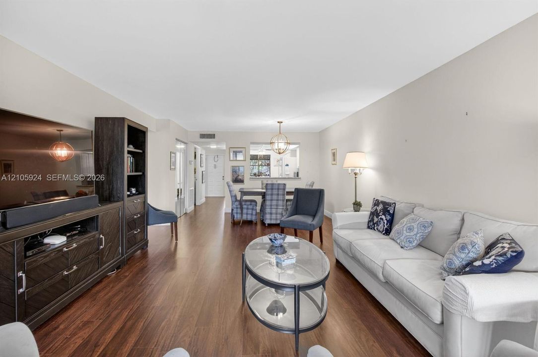 Open-concept interior featuring wood-finish flooring, a pass-through wall opening, and recessed lighting