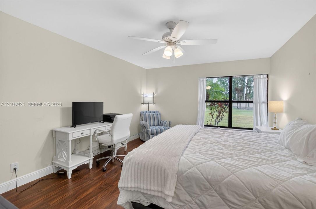 Wood-finish flooring, multi-light ceiling fan, and large picture window with exterior scenery