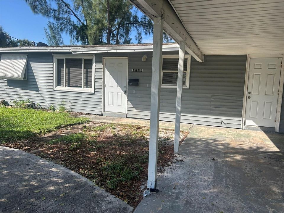 Horizontal siding exterior featuring a covered carport, two entry doors, and a metal window awning