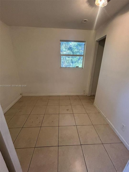 Interior space featuring neutral wall-to-wall ceramic tile flooring and a single-pane window