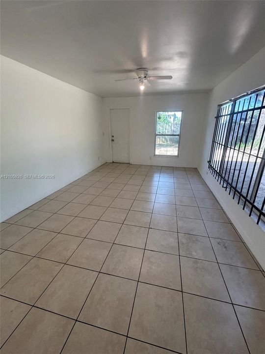 Interior space featuring ceramic tile flooring, a ceiling-mounted fan with light fixture, and windows equipped with metal security bars