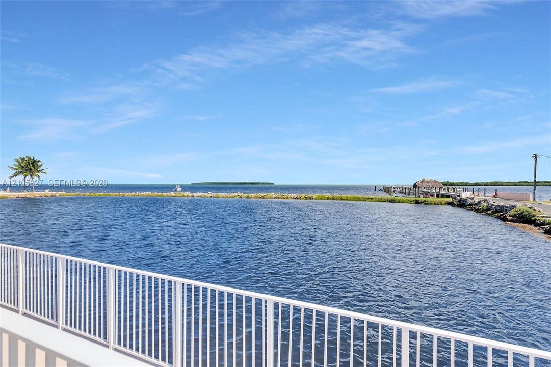 Waterfront property featuring a white metal railing, open water frontage, and a private dock